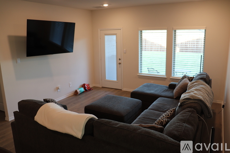 A person is sitting on a couch in a living room with a flat screen TV mounted on the wall.