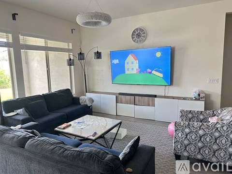 A living room with a blue couch and a television displaying a cartoon house.