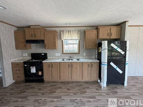 A kitchen with wooden cabinets and a black fridge.