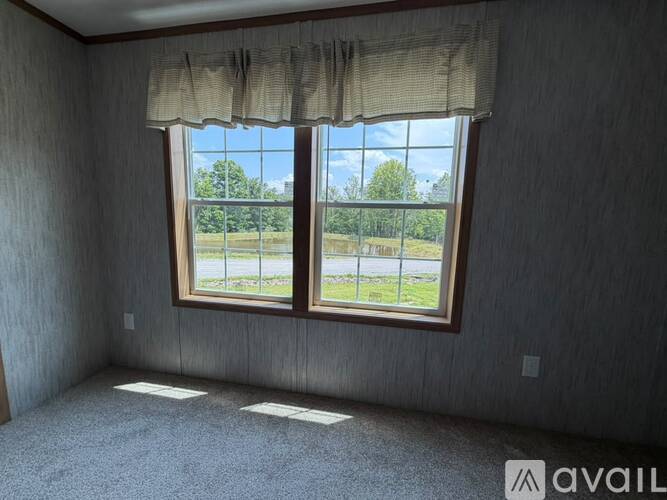 A room with a large window overlooking a grassy field.