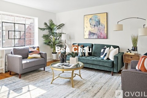 A living room with a green sofa, a grey armchair, a coffee table, and a painting on the wall.