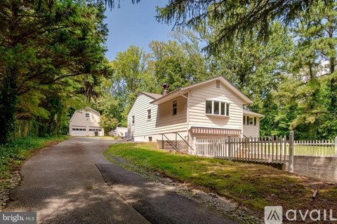 A house with a white picket fence is surrounded by trees.