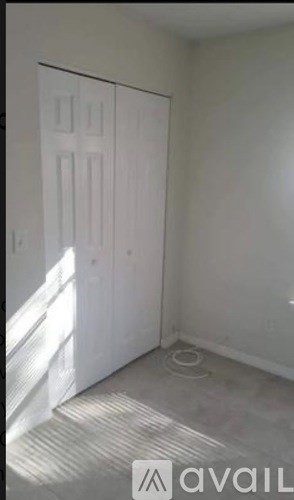 A room with a white door and a carpeted floor.