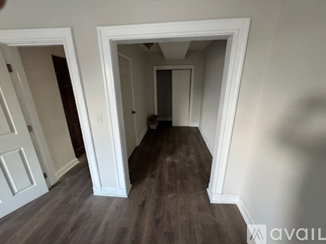 A hallway with white walls and a wooden floor.