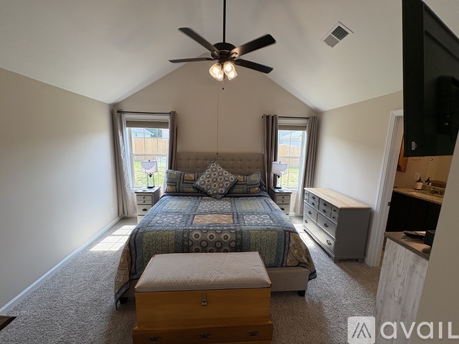 A bedroom with a bed, dresser, and ceiling fan.