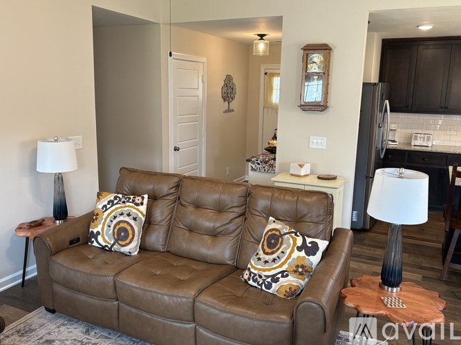 A brown leather couch with two decorative pillows sits in a living room.
