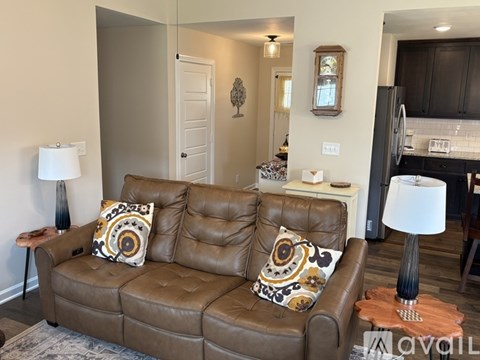 A brown leather couch with two decorative pillows sits in a living room.