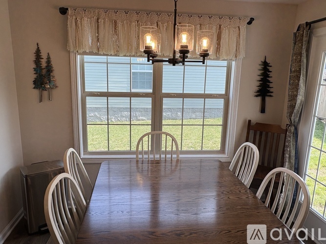 A dining room with a wooden table and white chairs.
