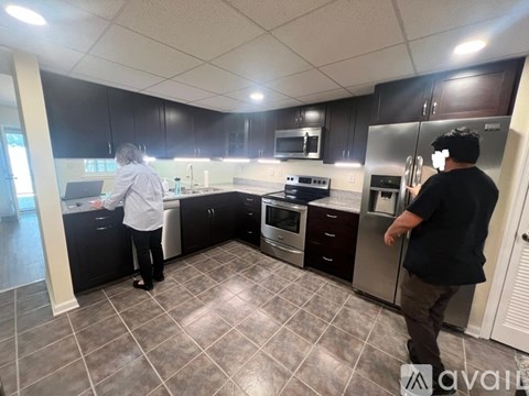 A man and a woman are in a kitchen with modern appliances.