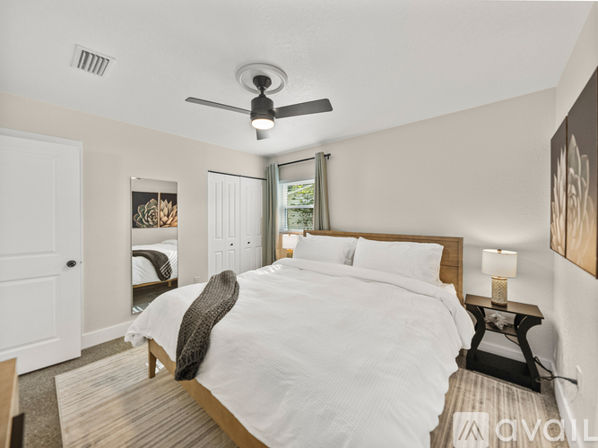 A bedroom with a large bed and a ceiling fan.