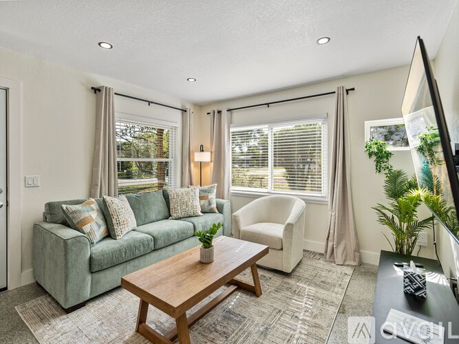 A living room with a green couch, a wooden coffee table, and a television.