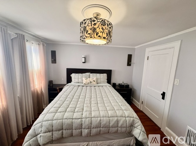 A bedroom with a large bed and a chandelier hanging from the ceiling.