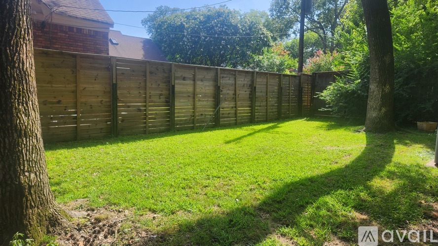 A backyard with a wooden fence and a tree.