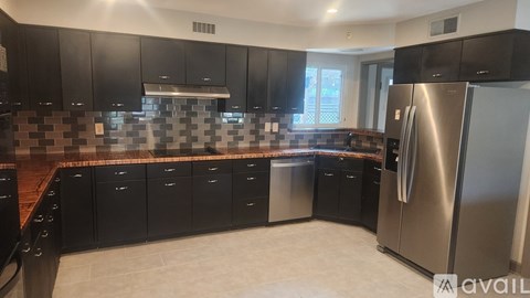 A kitchen with black cabinets and a checkered backsplash.