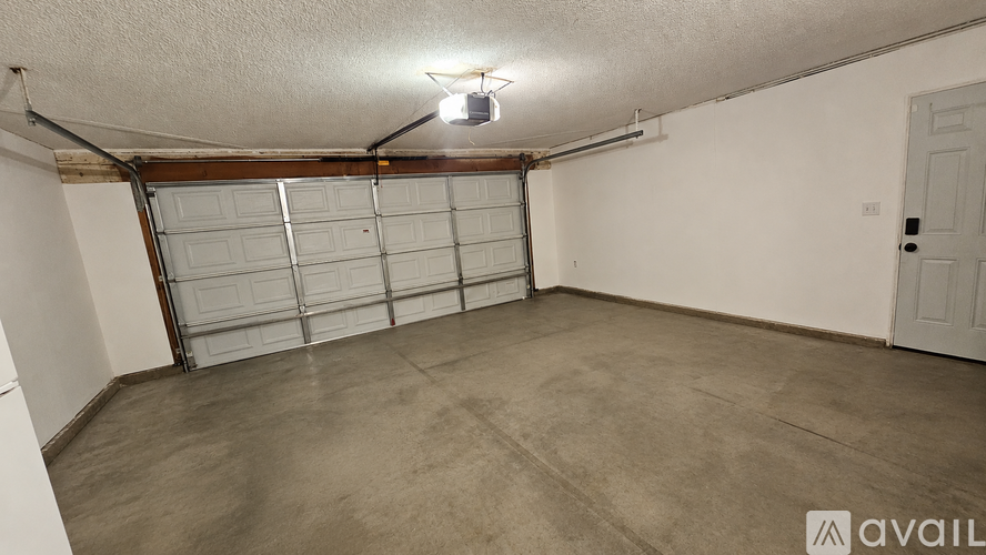 A spacious garage with a closed white door and a light on the ceiling.