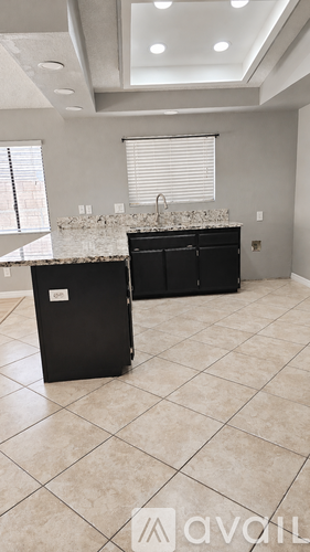 A kitchen with black cabinets and a marble countertop.