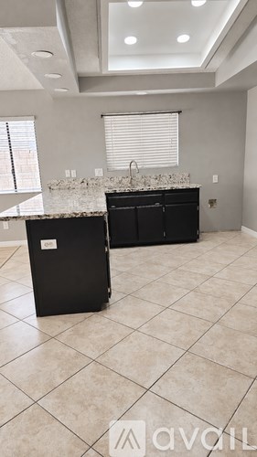 A kitchen with black cabinets and a marble countertop.