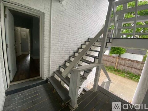 A staircase with a wooden handrail and steps leads to a doorway.