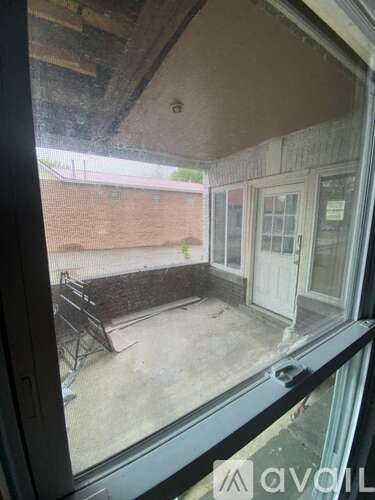 A view from inside a room looking out to a patio with a table and chairs.