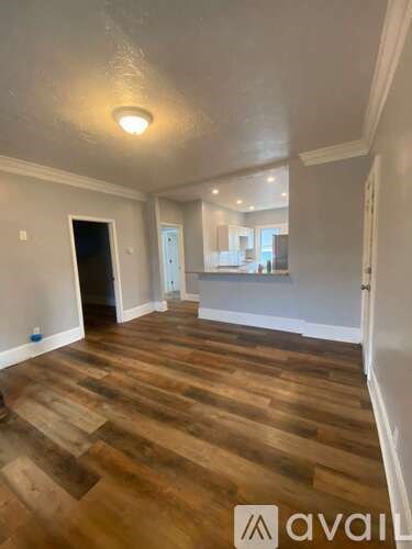 A room with wooden flooring and a doorway leading to another room.