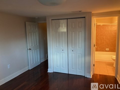 A room with a white door and a white closet with a white towel hanging on it.