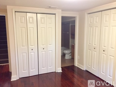 A room with white doors and a toilet in the background.