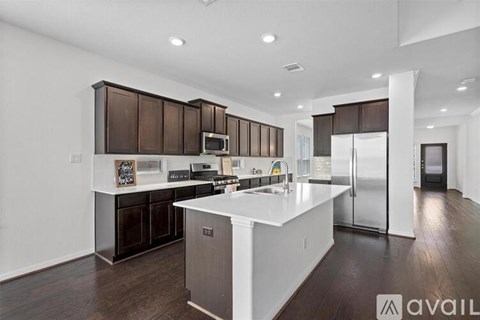 A modern kitchen with dark brown cabinets and stainless steel appliances.