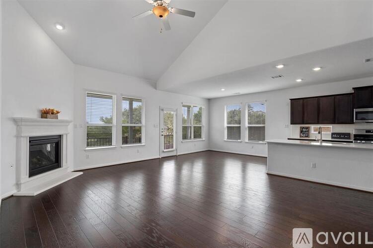 A spacious room with a fireplace and wooden flooring.