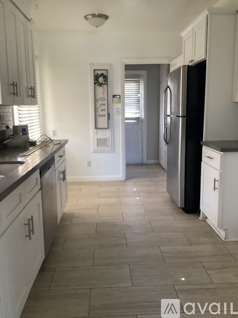 A kitchen with white cabinets and a black fridge.