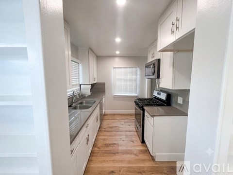 A kitchen with white cabinets and a wooden floor.
