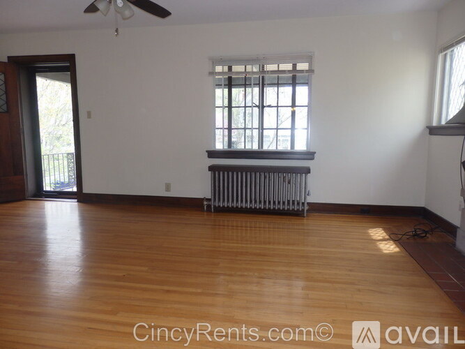A room with wooden floors and a window with a radiator beneath it.