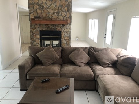 A living room with a brown couch and a stone fireplace.