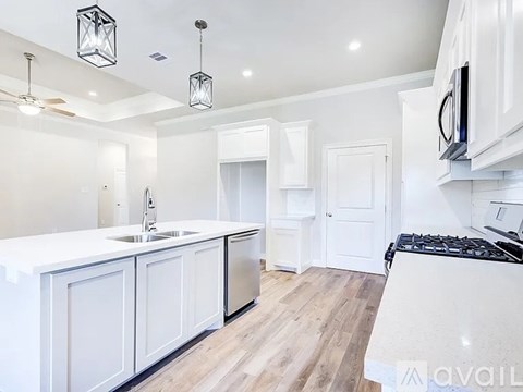 A modern kitchen with white cabinets and a wooden floor.