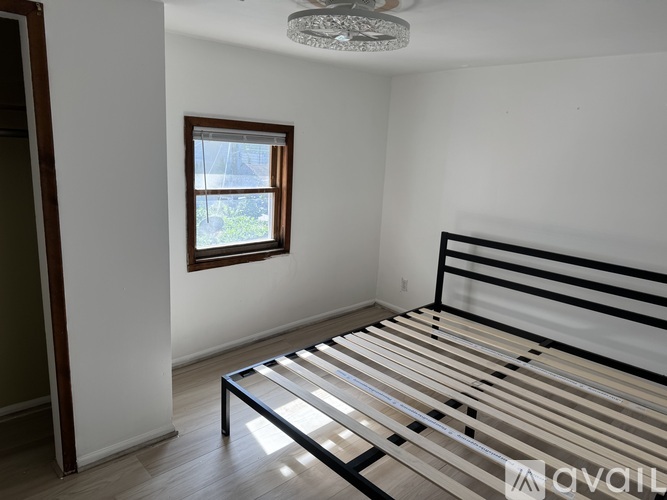 A bedroom with a bed, window, and wooden flooring.