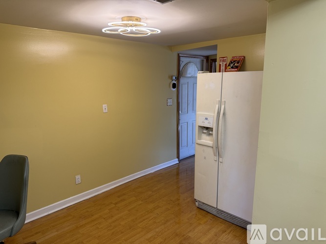 A room with a white fridge and a chair.