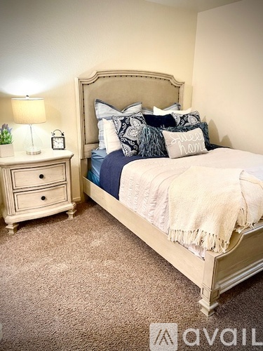A bedroom with a bed, nightstand, and lamp.