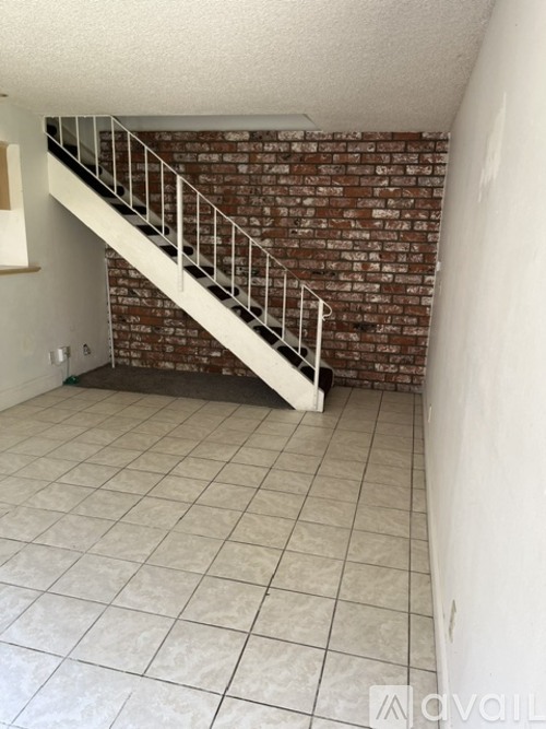 A staircase with a metal railing leads up to a brick wall.