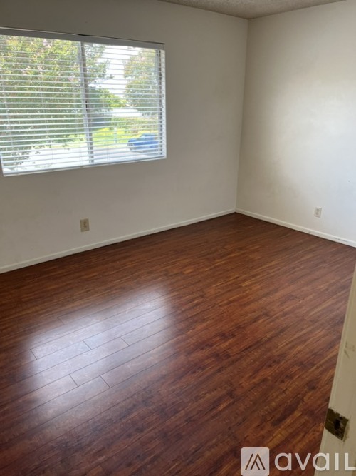 A room with wooden flooring and a window with blinds.
