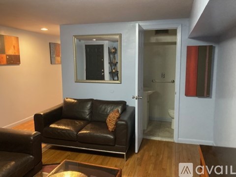 A black leather couch sits in a living room with a mirror above it.