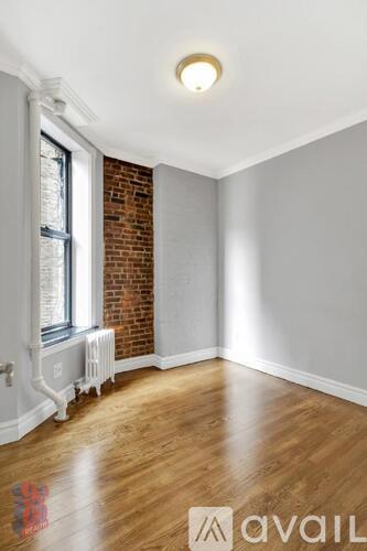 A room with wooden floors and a brick wall.