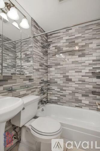 A bathroom with a toilet, sink, and a tiled wall.