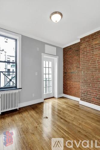 A room with a wooden floor and a brick wall.