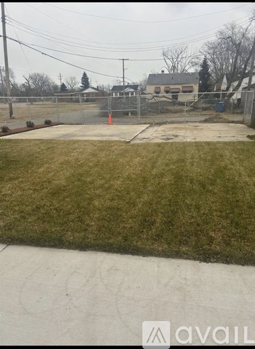 A grassy area with a fence and a building in the background.