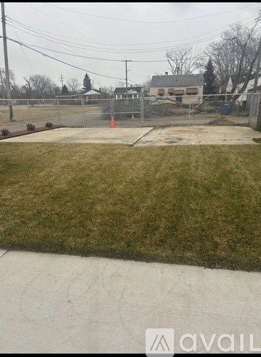 A grassy area with a fence and a building in the background.