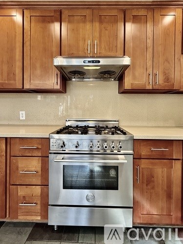 A kitchen with a stove and wooden cabinets.