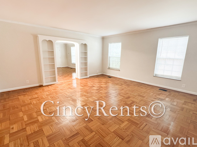 A room with wooden flooring and white walls, with a window on the right side.