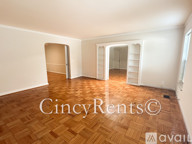 A room with wooden flooring and white walls, with two open doors.