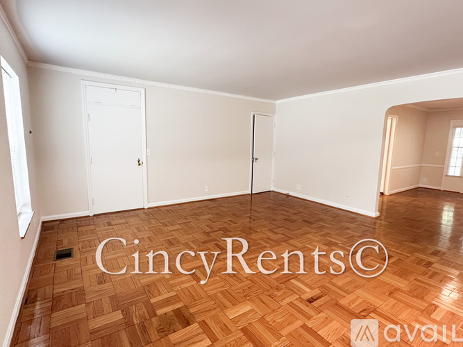 A room with wooden flooring and white walls, with a door and a window.