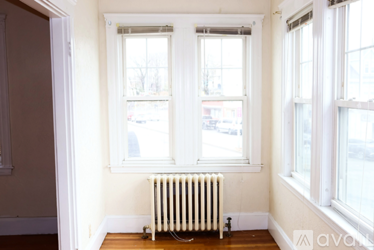 A white radiator sits in front of a window in a room.