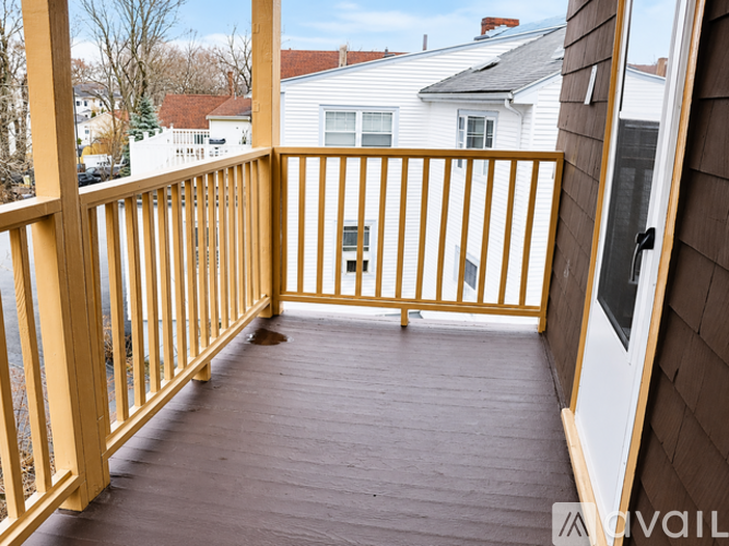 A wooden deck with a railing and a view of a residential area.